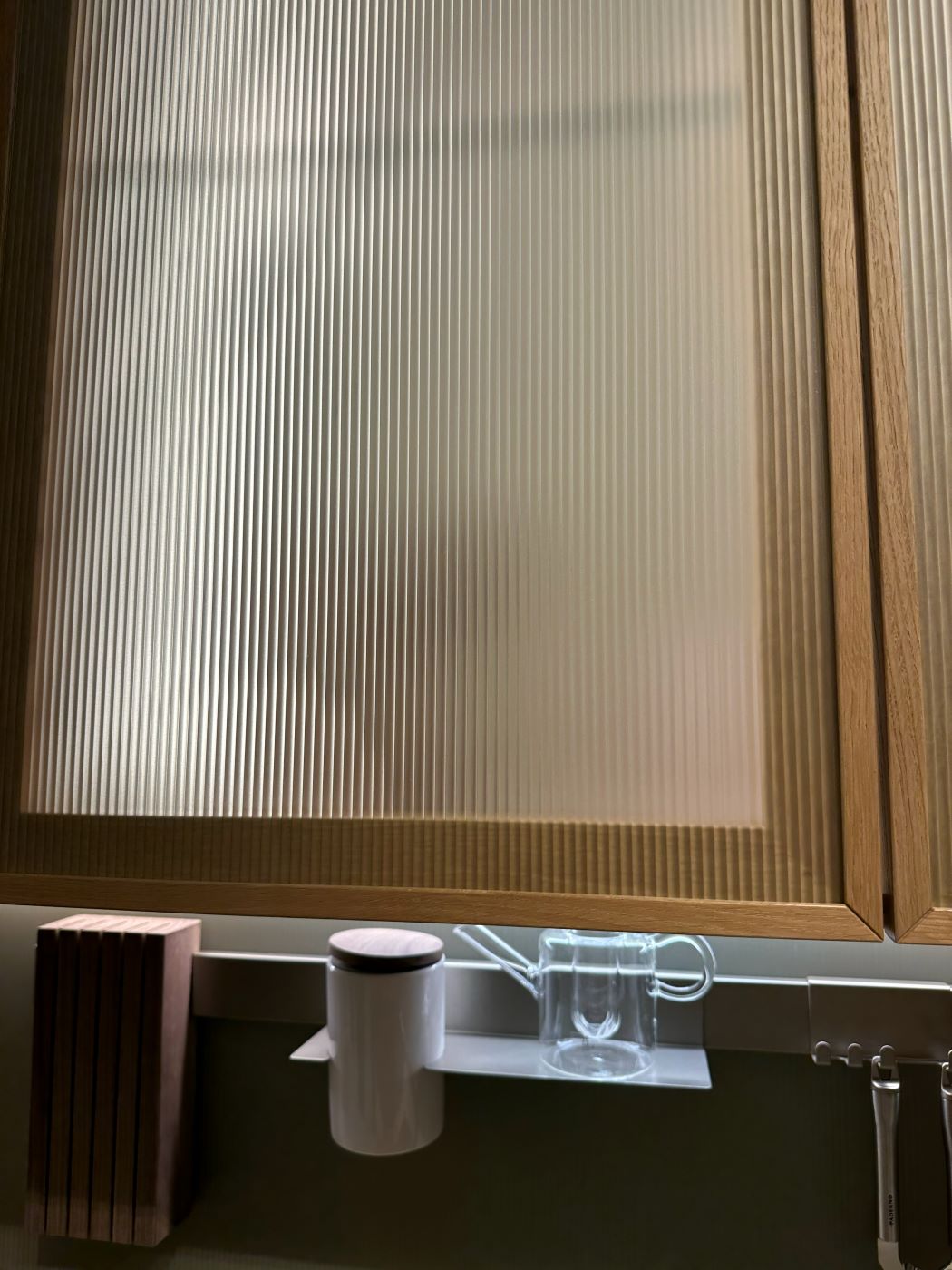 Verre flûté et bois foncé texturé — façade de meuble Salone del Mobile 2026